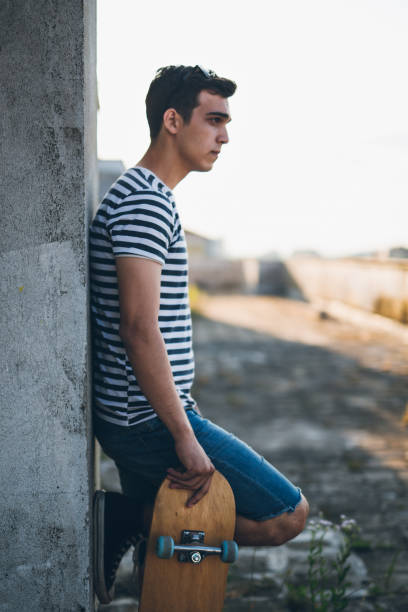 istock Handsome young skater standing against wall 802938298