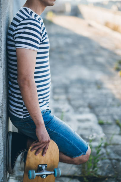istock Handsome young skater standing against wall 802938332
