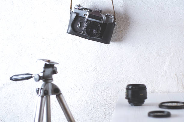 istock Old camera and tripod on a white concrete background 802941236