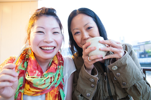 2 Japanese women enjoying drink and cake