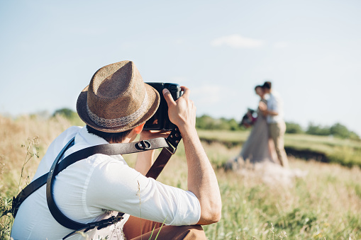 wedding photographer takes pictures of bride and groom in nature in summer, fine art photo