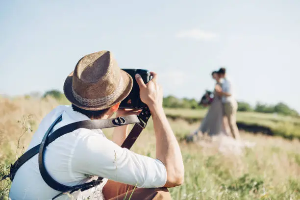 Photo of wedding photographer takes pictures of bride and groom in nature, fine art photo