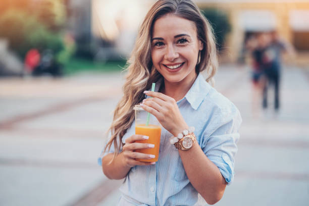 Beauty and health Beautiful woman drinking fresh juice outdoors preppy fashion stock pictures, royalty-free photos & images