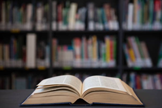 Close up of open book on table against shelf