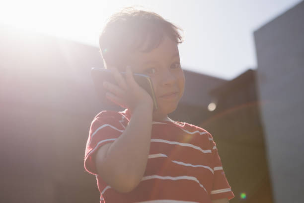 istock Low angle view of boy talking on mobile phone while standing against sky 802987142