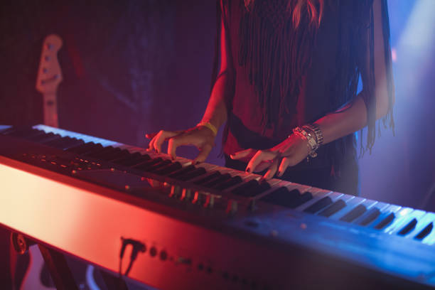 istock Female playing piano in illuminated nightclub 802990696
