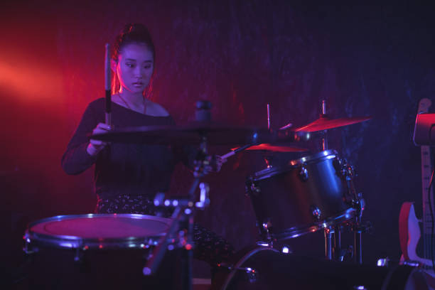 istock Female drummer playing drum kit in illuminated nightclub 802990828
