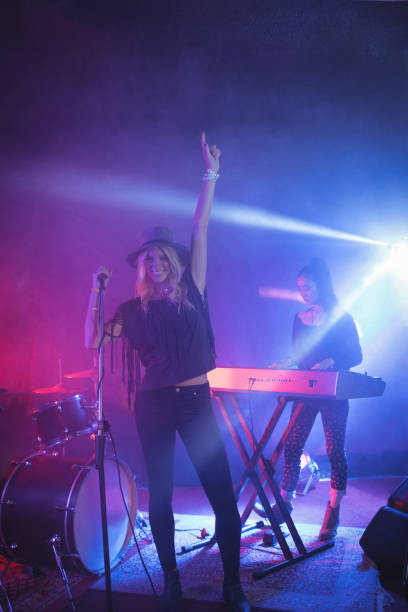 istock Cheerful singer singing while musician playing piano in illuminated nightclub 802991480