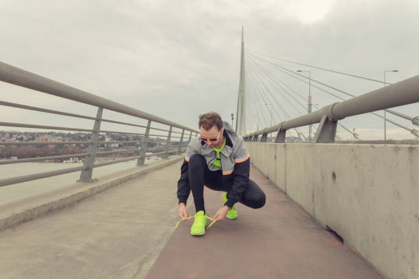 istock Man tying running shoes on a big bridge. 802994284