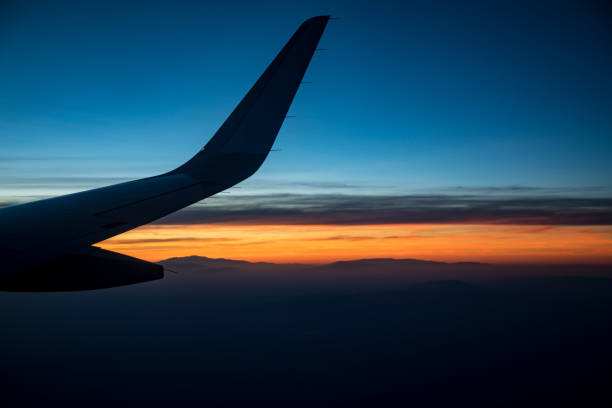 istock View of airplane wing flying at sunset 802998030