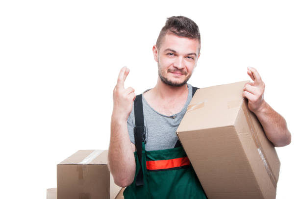 istock Smiling mover guy holding cardboard box showing fingers crossed 802998172
