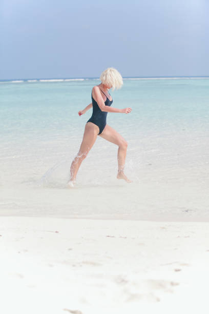 istock Woman in bikini running through water on sandy beach, Maldives 803005164
