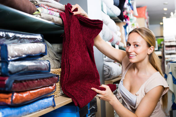 istock Portrait of laughing woman choosing blanket 803024708