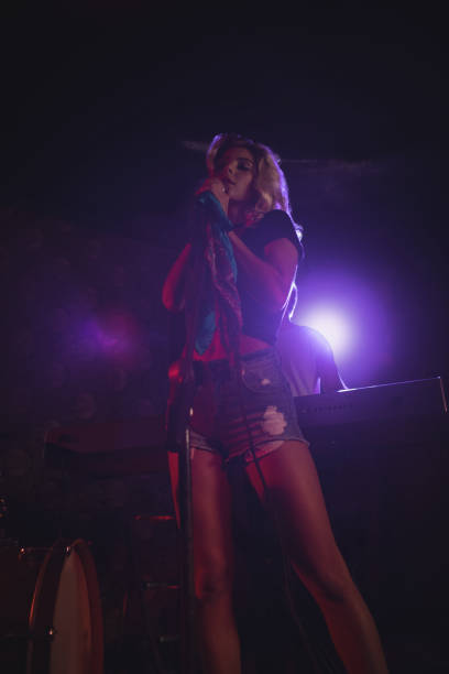 istock Female singer standing on illuminated stage in nightclub 803057662