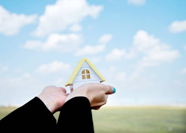 Close-Up Of Human Hand Holding Model Home Cut Out