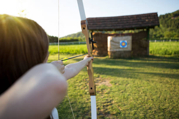 istock Female archer aiming bullseye 803091382