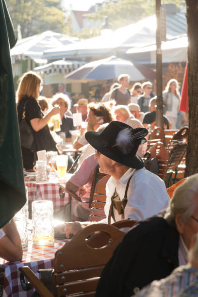 Munich, Germany - September 29, 2016: Viktualienmarkt beer garden is located at Munich's central food market. People sitting at the wooden tables and enjoying the sunny weather. They are drinking Beer and eating traditional Bavarian meals.