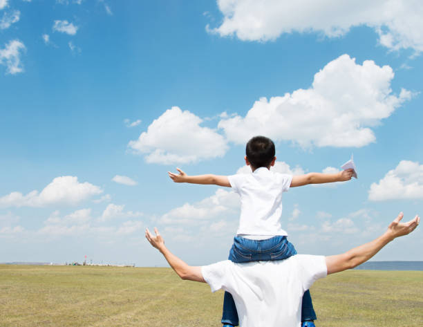 istock Son and father play paper airplane in the field 803101890