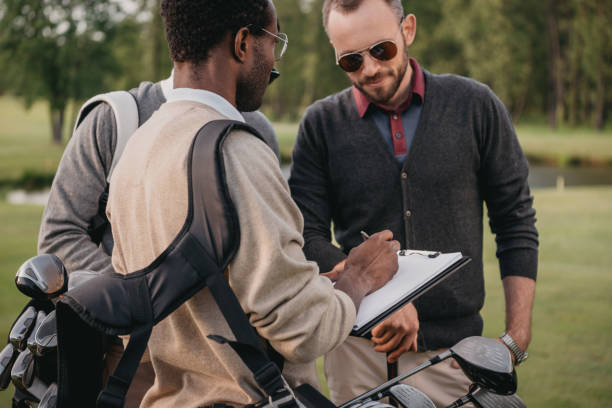 istock african american man writing in clipboard while looking on two golf players 803113998