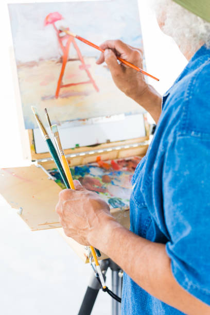 istock Mature Latin man painting at the beach 803118738