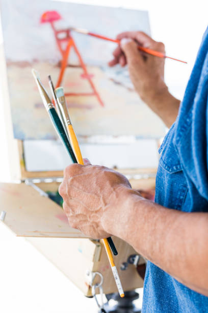 istock Mature Latin man painting at the beach 803119338