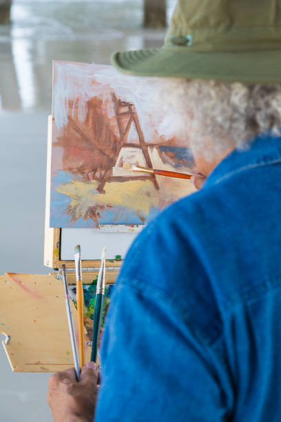 istock Mature Latin man painting at the beach 803119762