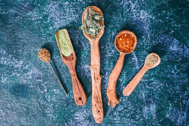 Dried herbs for cooking Dried chili peppers, cilantro, tarragon thyme and lemon balm in various spoons over dark blue spotty background. Top view tarragon cutting board vegetable herb stock pictures, royalty-free photos & images