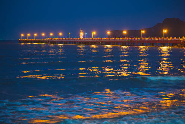 Prachuap Khiri Khan city pier at night. Waves and lights in the sea darkness.