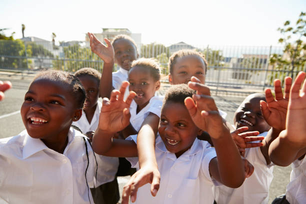 istock Elementary school kids in playground waving to camera 803138156
