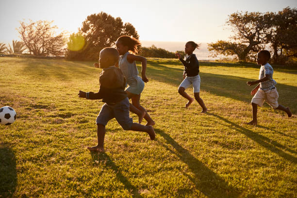 istock Four elementary school kids playing football in a field 803138308