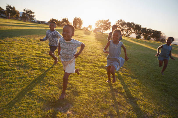 One boy and two girls running across green lawn