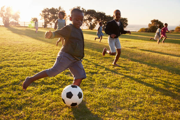 escuela primaria a los niños jugando al fútbol en un campo - ball horizontal outdoors childhood fotografías e imágenes de stock