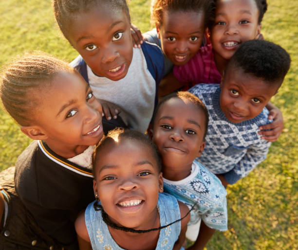 istock Elementary school kids in a field look up at  camera smiling 803138414