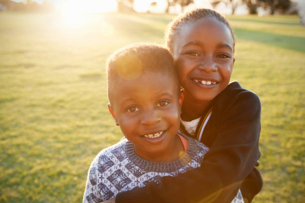 afrikaanse basisschool jongen en meisje knuffelen buitenshuis - broer en zus stockfoto's en -beelden