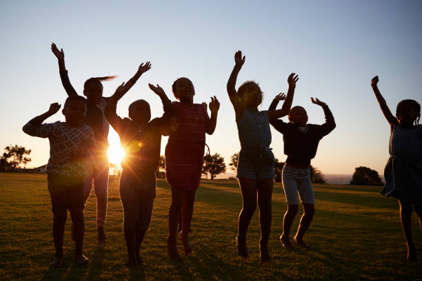 istock Silhouetted school kids jumping outdoors at sunset 803138676