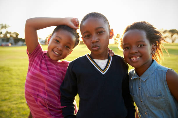 istock Three African elementary schoolgirls pose to camera in field 803138772