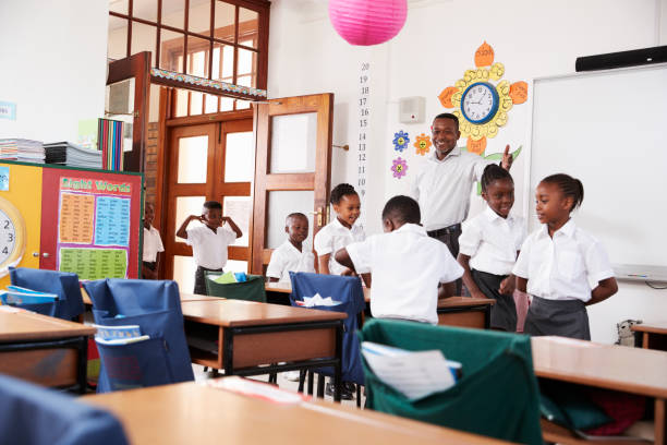 istock Teacher welcomes kids arriving to elementary school class 803138858