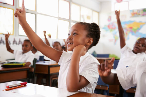 小学校で授業中に手を上げる女子高生 - elementary school waist up indoors childhood ストックフォトと画像