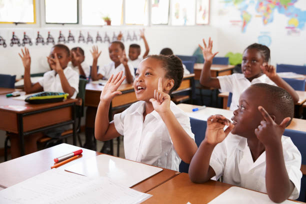niños con las manos durante una clase en una escuela primaria - africa african descent education child fotografías e imágenes de stock