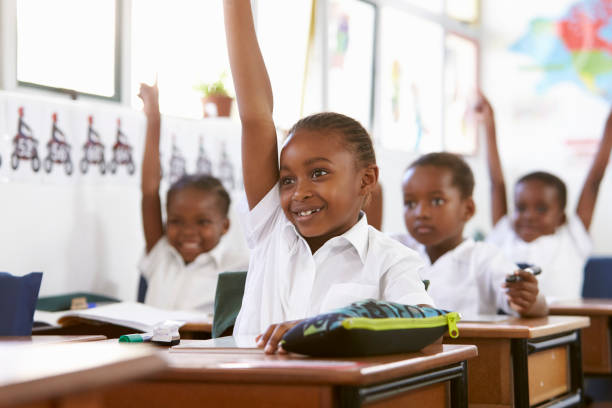 elevar las manos durante una clase en una escuela primaria de niños - africa african descent education child fotografías e imágenes de stock