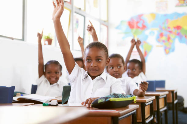 小学校で授業中に手を上げる子供たち - elementary school waist up indoors childhood ストックフォトと画像