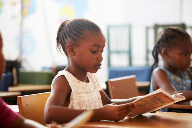 本を保持していると小学生のレッスンを読んで女の子 - elementary school waist up indoors childhood ストックフォトと画像