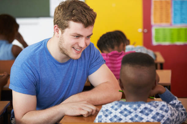 istock White male Volunteer teacher helping boy in elementary school class 803154894