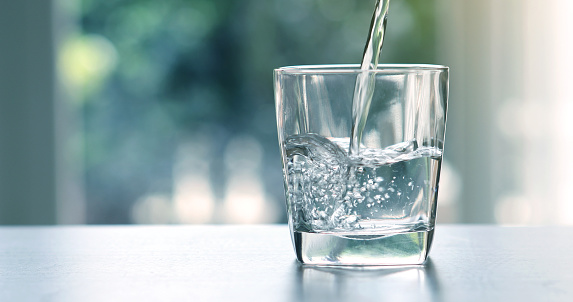 Verter el agua purificada fresca bebida de la botella sobre la mesa en la sala de estar de cerca photo