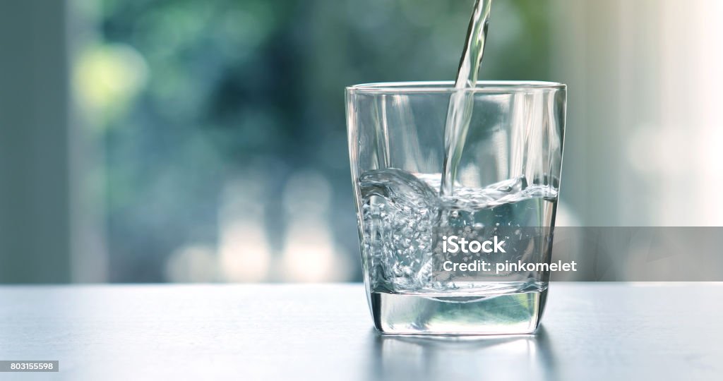Verter el agua purificada fresca bebida de la botella sobre la mesa en la sala de estar de cerca - Foto de stock de Agua libre de derechos