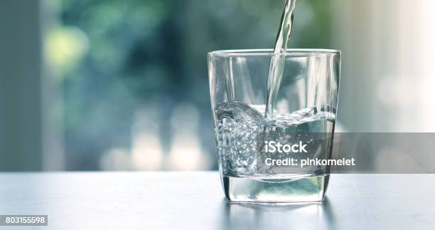 Close Up The Pouring Purified Fresh Drink Water From The Bottle On Table In Living Room Stock Photo - Download Image Now