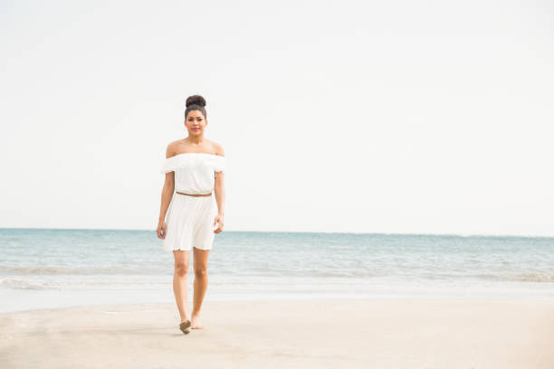 Stylish woman walking on the sand at the beach