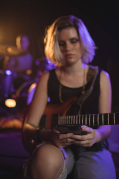 istock Guitarist using mobile while sitting in nightclub 803165400