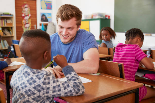 istock White male teacher helping elementary school boy in class 803168014