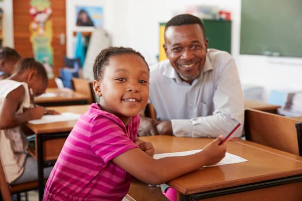 istock Black teacher and elementary school girl smiling to camera 803170688